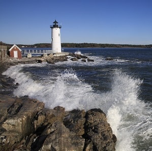 Lighthouse along coast line with big waves.
